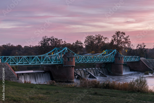 Water weir in Wroclaw, Poland, called "Jaz Bartoszowice". Element of water engineering. Beautiful architecture with towers and bridge. Waterfall on Oder river.