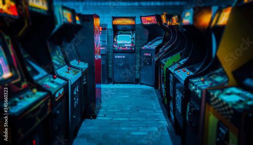 Arcade video games in an empty dark gaming room with purple light with glowing vintage displays and beautiful old retro design