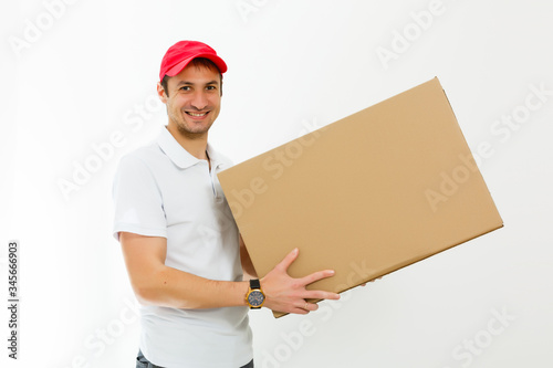 Smiling young delivery man holding and carrying a cardbox isolated on white background