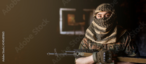 Arab male soldier in a headdress from the national keffiyeh with weapons in his hands. Muslim man with guns on black