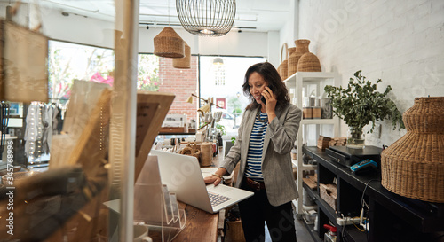 Smiling Asian woman talking on a cellphone in her store