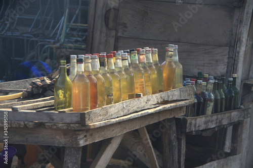 butelki i baniaki z benzyną na drewnianym stoliku przy drodze wystawione na sprzedaż na afrykańskiej prowincji