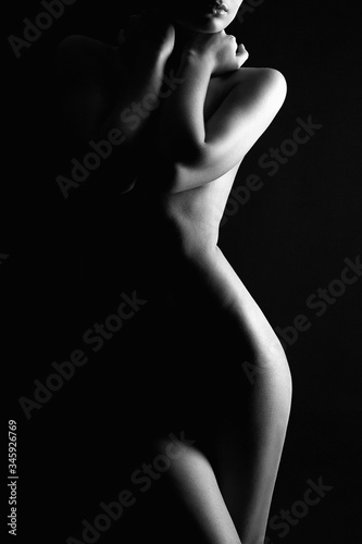 Nude Woman silhouette under light in the dark