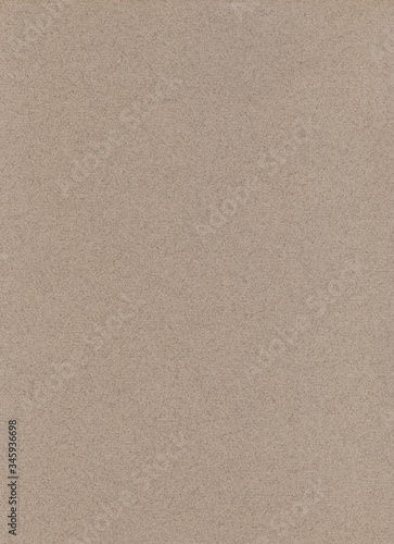 Beige or light taupe paper background. Wet sandy colored pastel paper. Blotches and hairs on a uniform texture. Abstract homogeneous flatlay, top view. Vertical format. Free space for your text.