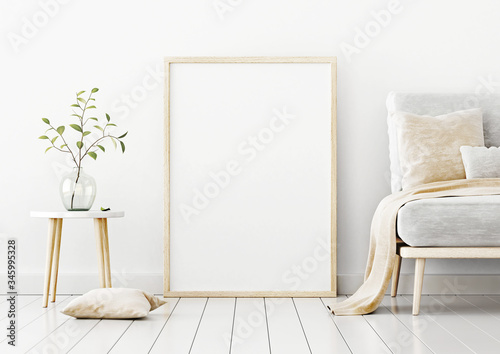 Poster mockup with vertical frame standing on floor in living room interior with sofa, beige pillow and branch in glass vase on empty white wall background. 3D rendering, illustration.