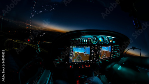 Lightened up cockpit and avionics in aircraft flying at night with beautiful twilight in background