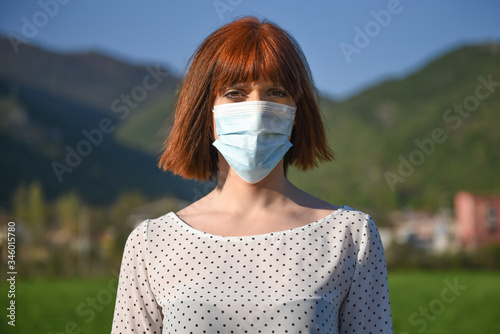 Girl in protective mask with flowers on the background of nature. Post-apocalypse survival after the covid-19 coronavirus pandemic. World after global catastrophe