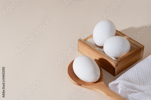 Chicken eggs in a wooden box on beige background with copy space, product with amino acids choline lecithin cholesterol calcium potassium phosphorus magnesium iodine protein vitamins healthy diet food