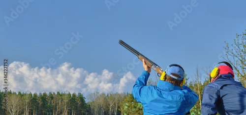 athlete shoots at clay pigeon under the guidance of a shooting coach, panoramic banner , Copy Space