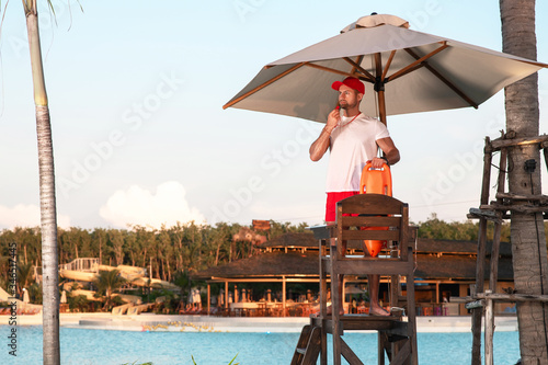 A responsible lifeguard man stands on a tower and is ready to save tourists bathing in the water.