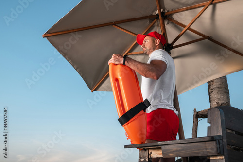 Portrait of a young lifeguard with a rescue orange buoy. Security measures on the beach.