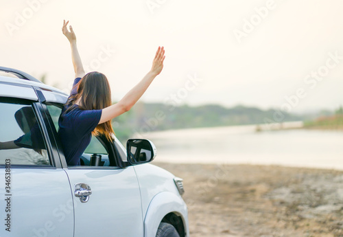 Young happy woman raise her hands out of white SUV car window while roadtrip, Travel car in vacation