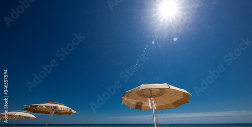 ombrelloni aperti e sullo sfondo mare e cielo blu e un motoscafo pronto a partire