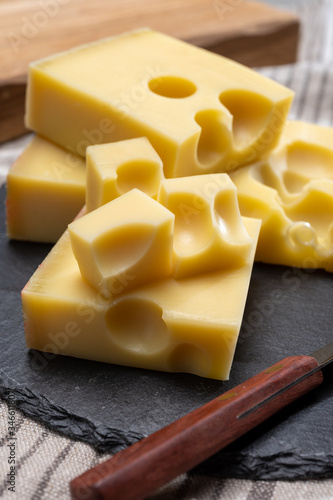 Block of Swiss medium-hard yellow cheese emmental or emmentaler with round holes and cheese knife