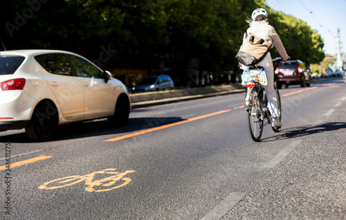 Cycle lane with orange painted bike on asphalt. Bicycle lane and car traffic. Ecological green urban transport. Fahrradspur und Autoverkehr. Fahrrad Zeichen auf Straße. Ökologischer urbaner Verkehr.
