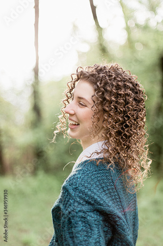 Portrait of laughing and smiling girl with curly hair on green and wooden background