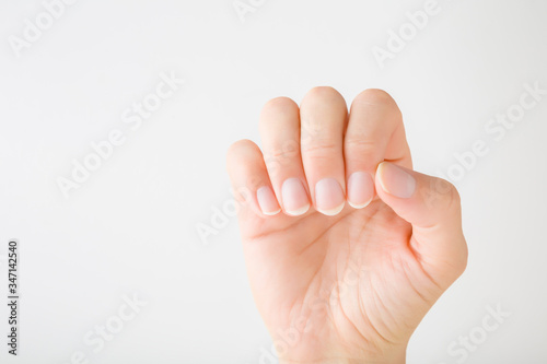 Young woman hand without nail polish on light gray background. Showing healthy natural nails. Simple manicure. Closeup. 