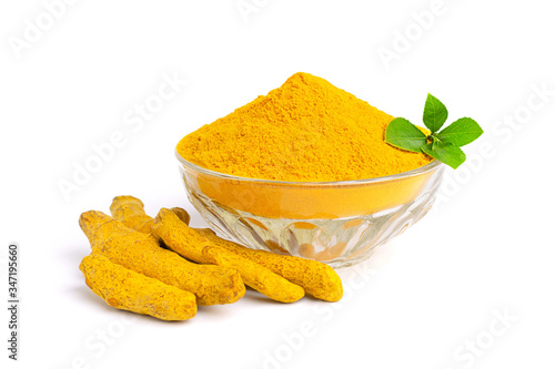 Turmeric powder in glass bowl with green leaves and dry roots isolated on white background.