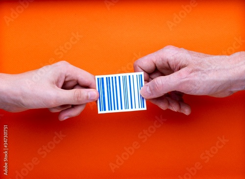 Illustration identification permanente des personnes et des biens, un code barre imprimé tenu par deux mains en opposition, sur fond orange
