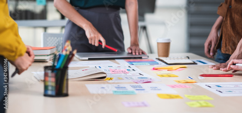 Close up ux developer and ui designer brainstorming about mobile app interface wireframe design on table with customer brief and color code at modern office.Creative digital development agency.panning