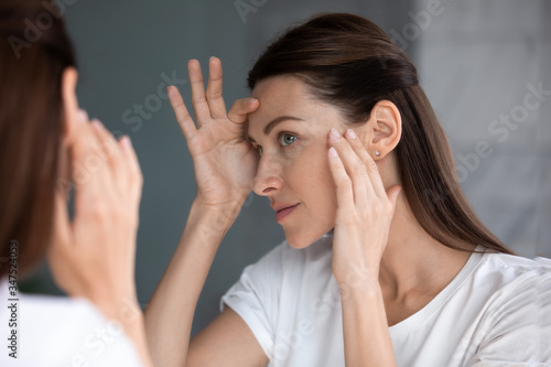 Close up of woman looking in mirror check face after mask cream beauty treatment feels satisfied admire reflection, laser skin resurfacing, glycolic acid peel, anti-ageing skincare procedures concept