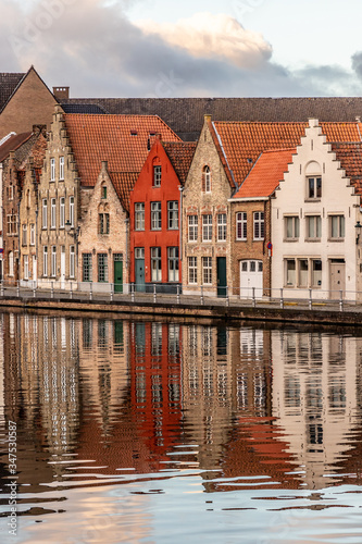 Buildings with reflections around channels in Bruges at sunset