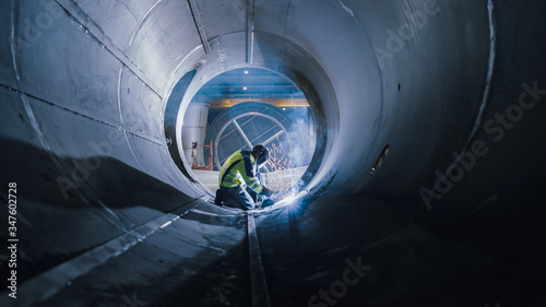 Professional Heavy Industry Welder Working Inside Pipe, Wears Helmet and Starts Welding. Construction of the Oil, Natural Gas and Fuels Transport Pipeline. Industrial Manufacturing Factory