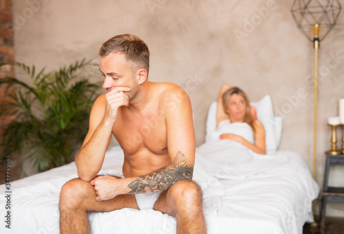 Couple sitting unsatisfied on bed in bedroom