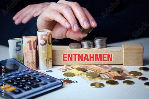 Entnahmen. Männliche Hand stapelt Geld-Turm (Euro). Begriff an Baustein. Münzen, Scheine & Taschenrechner. Konzept für Business, Finanzen, Statistik