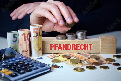 Pfandrecht. Männliche Hand stapelt Geld-Turm (Euro). Begriff an Baustein. Münzen, Scheine & Taschenrechner. Konzept für Business, Finanzen, Statistik