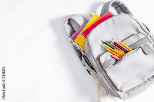 Back to school concept. Backpack with school supplies, pens, pencils, notebook on white background. Flat lay, top view, copy space