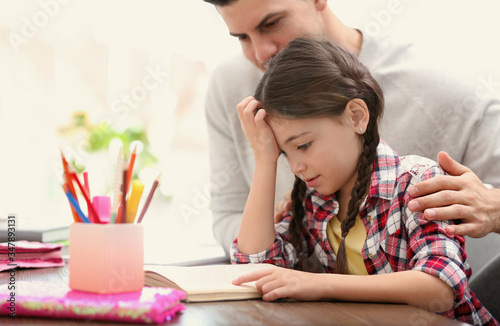 Man helping his daughter with homework at table indoors