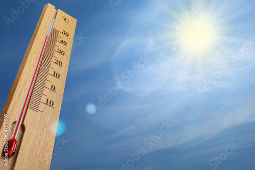 Wooden thermometer with red measuring liquid showing 40 degrees Celsius on a sunny day.