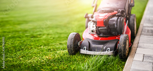 Lawn mover on green grass in modern garden.