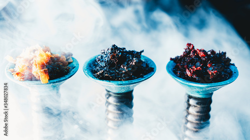 Side view of different kinds of hookah tobacco on smoky bar counter