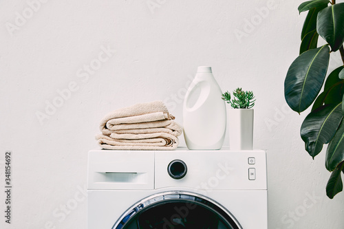 Detergent bottle and towels on washing machine and green plant in bathroom