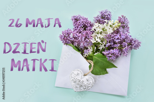 flat lay with white and purple lilac blossoms in envelope with inscription in Polish language translated as May 26th Mothers Day