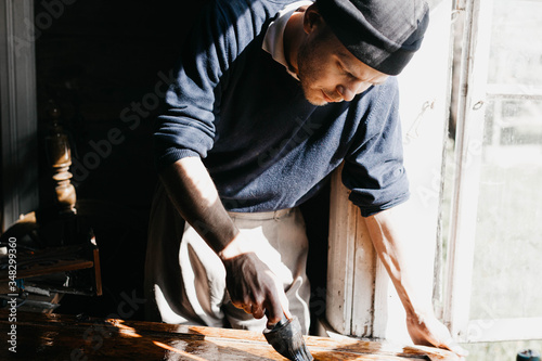 male artisan processes an array of wood with epoxy varnish. renovation of antique furniture.