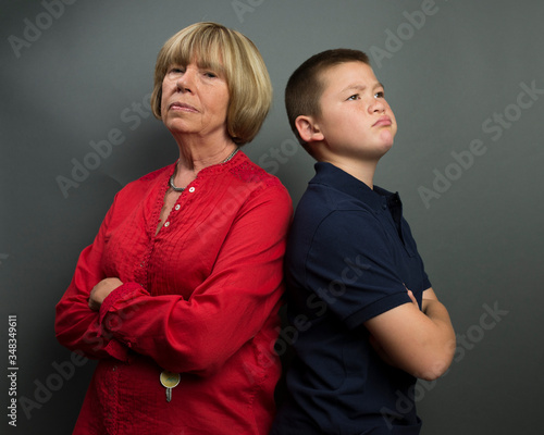 Mother and son back to back with arms folded in stubborn opposition.