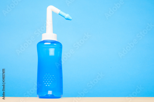 blue water pulse nasal wash bottle on a blue background, nasal irrigation concept