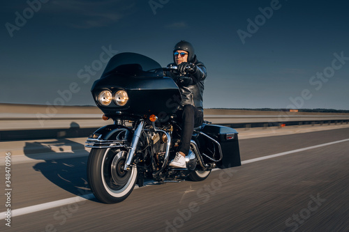 Motorcycle driver riding alone on asphalt motorway. Biker go fast at the empty hightway