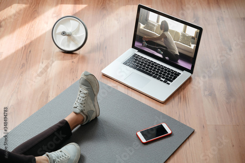 Closeup of young fit woman training indoors using laptop for watching yoga classes online. Home online workout. Home fitness during pandemic, quarantine and self isolation
