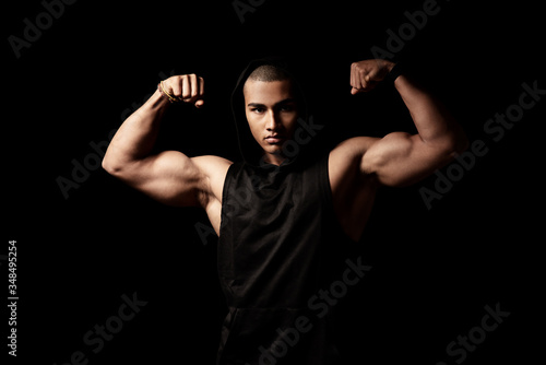 Attraktiver muskulöser junger Mann posiert mit angespannten Muskeln, Portrait vor schwarzem Hintergrund mit copy space 