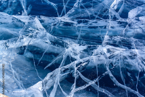 Many beautiful cracks in the clear blue ice. Layered thick ice. Horizontal.