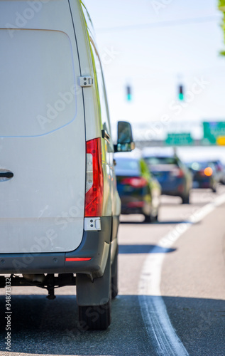 Commercial cargo mini van driving on the city road with traffic light and signs