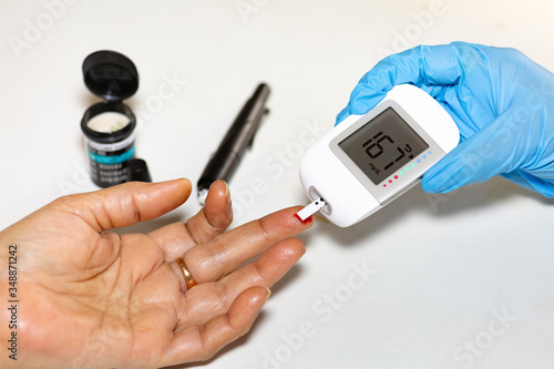 Medical examiner taking blood sample from a female patient for instant blood sugar measurement shot with selective focus