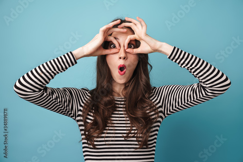 Image of amusing young woman making fun with fingers