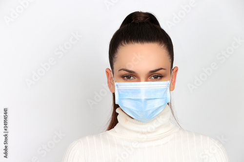 Jeune femme brune portant un masque chirurgical pour se protéger des virus isolée sur fond blanc