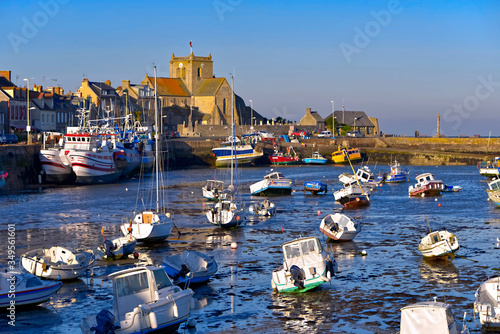 Port at low tide at the end of the sunny day and church of Saint-Nicolas of Barfleur, a commune in the peninsula of Cotentin in the Manche department in Lower Normandy in north-western France