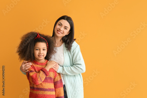 Happy woman with little adopted girl on color background